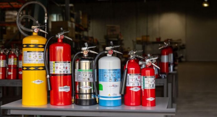 a row of various Summit Fire Protection portable fire extinguishers including a Class D, Class ABC, Restaurant, Water Mist, Carbon Dioxide, and Halotron extinguisher